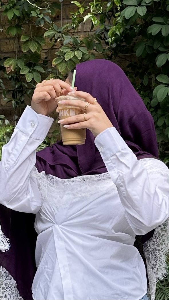 Aya the Label — model in a purple lace-trim hijab sipping coffee in a garden café.