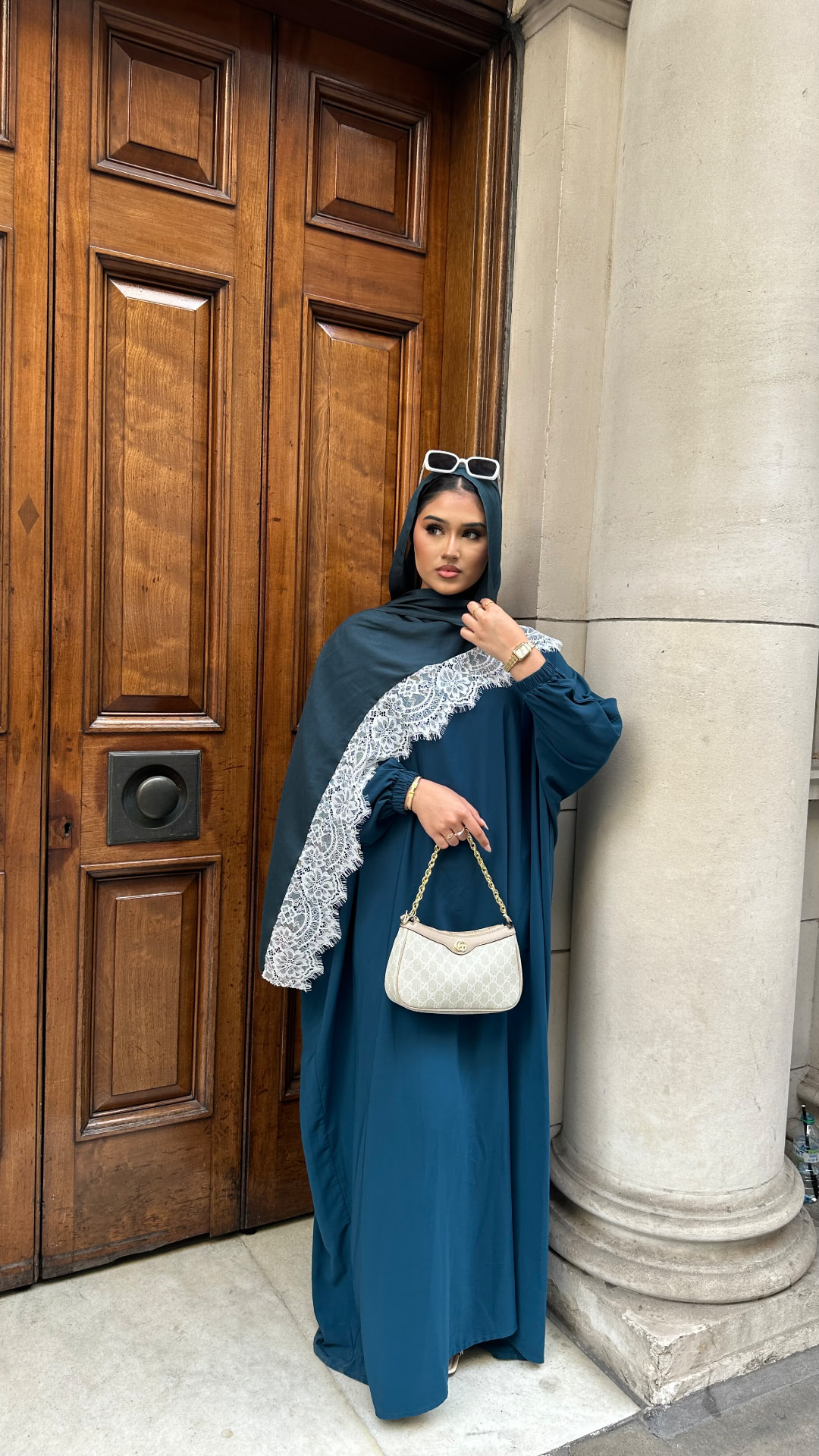 Full length shot of a model in a teal/emerald lace look standing in a doorway.